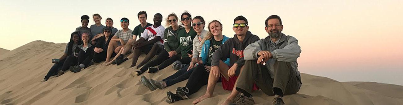 Global Health students and staff sitting on a sand dune