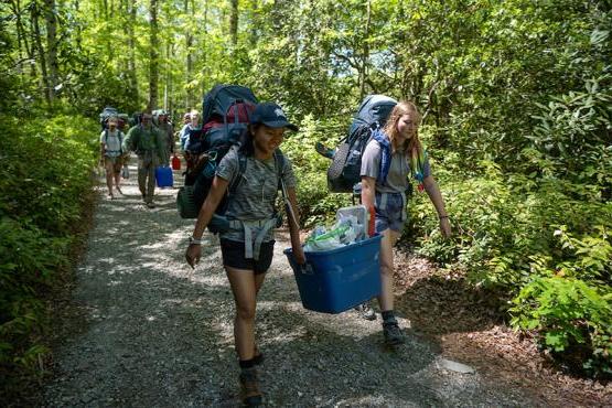 Ohio University students hike with backpacks on a forest trail